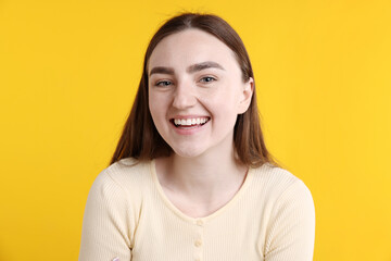 Fototapeta premium Portrait of young woman laughing at joke on yellow background