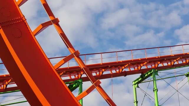 Empty roller coaster car rapidly descends a steep, curving orange track, offering an exhilarating perspective of the thrilling amusement park ride