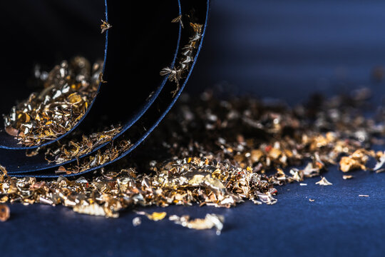 Closeup of brass metal filings scattered on black cardboard, abstract shapes and texture, nonferrous metal structure and industrial processing concept