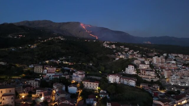 Scalea, Italy - 25.09.2025 Aerial view of a forest fire on a mountain slope above the city at night