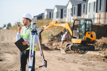 Surveyor using total station and radio at construction site