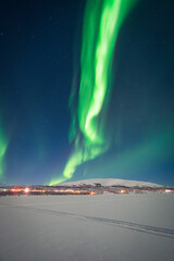 Full moon and Aurora Borealis glowing over a frozen Arctic landscape © Renatas