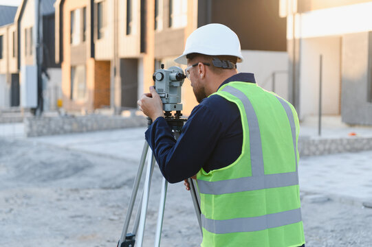 Surveyor using theodolite measuring at construction site