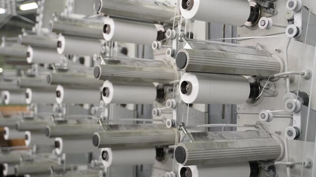 Industrial textile machine weaving fabric with spools
