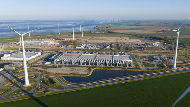 Aerial view of the Google Data Center surrounded by wind turbines and green fields near the coast in Eemshaven, Groningen, Netherlands.