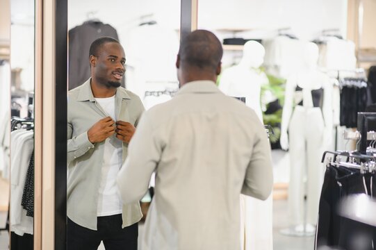 Stylish man trying on clothes in a fashion store mirror