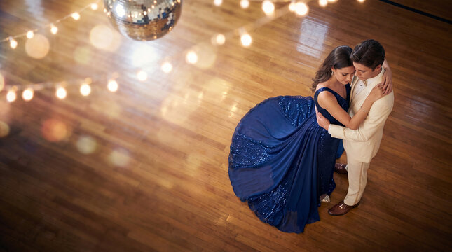 Couple slow dancing in elegant attire under disco lights  