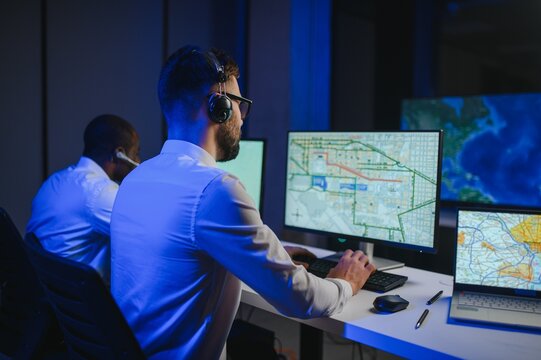 Center of dispatching maintenance. Portrait of men working via headset microphone while sitting on navigation controller board