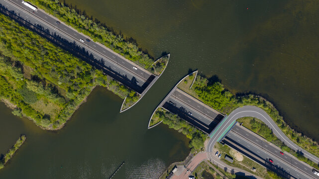 Aerial view of the Aquaduct Veluwemeer with cars driving on the road passing under the water bridge surrounded by lush green trees Harderwijk, Gelderland, Netherlands.