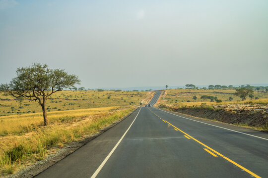 Long asphalt road winding through the African savanna under a clear sky