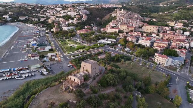 Horizontal aerial right side view of Torre Talao tower and Scalea cityscape, Italy