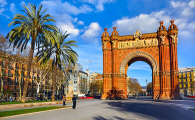 Obraz premium Barcelona, Catalonia, Spain. Triumphal Arch. Arc de Triomf at boulevard street. Alley with tropical palm trees. Early morning landscape with shadows and blue sky with clouds. Famous landmark.