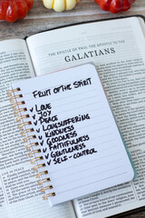 Obraz premium Christian fruit of the spirit (love, joy, peace) text in a notebook with Galatians holy bible on wooden background. Biblical concept.