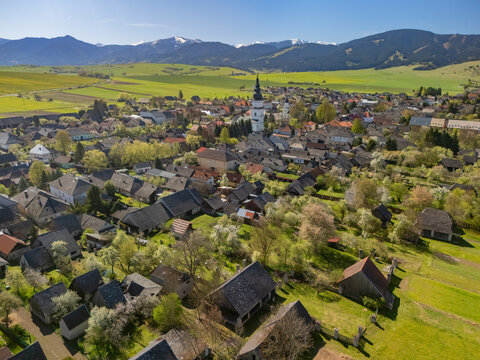 Aerial view of the historic village with its church tower, traditional houses, and mountains in the background Partizanska Lupca, Zilina Region, Slovakia.