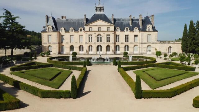 Starting camera push revealing large pale-stone chateau at formal gardens, with oval fountain jets