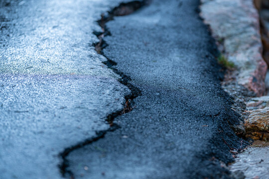 Close view of cracked asphalt road surface showing damage and wear detail.