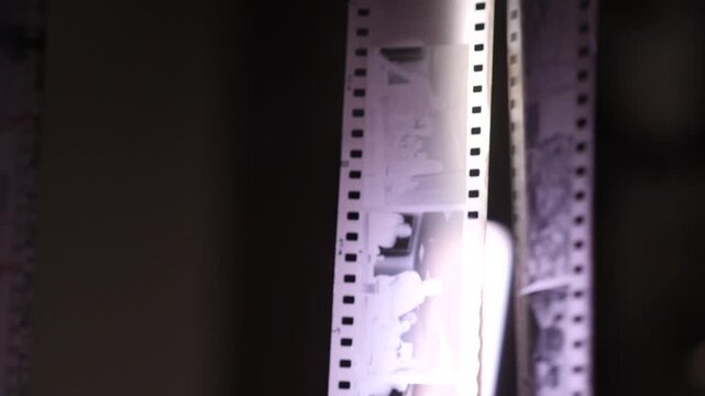 Negative film strip hanging to dry after darkroom development, close up of frames and glossy surface catching light vintage analog photography evoking nostalgia and memory