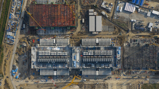 Aerial view of the Bridge Data Center under construction with large industrial buildings, cooling systems, and construction cranes in Khlong Tamru, Chon Buri, Thailand.