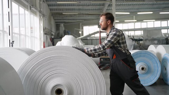 Factory worker pushing huge spunbond polypropylene roll