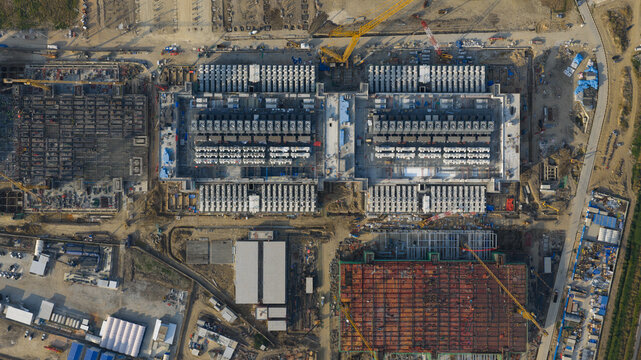 Aerial view of Bridge Data Center under construction showing industrial structures, cooling systems, and yellow cranes on a large site Khlong Tamru, Chon Buri, Thailand.