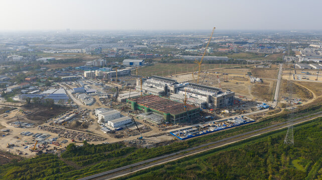 Aerial view of the Bridge Data Center under construction with cranes, industrial buildings, and vast landscape in Khlong Tamru, Chon Buri, Thailand.