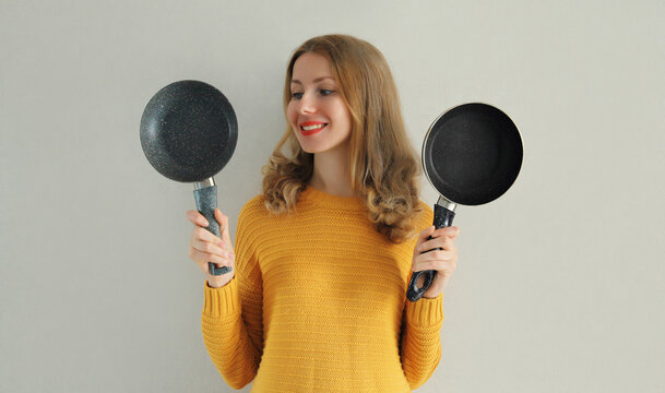 Cooking mood, portrait of happy smiling young woman housewife with empty frying pan