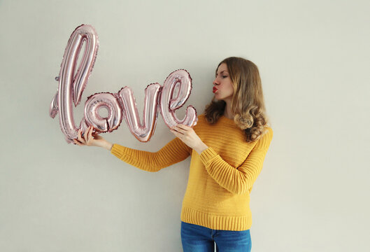 Woman holding word love, letters shaped foil balloons
