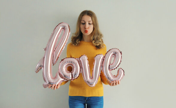 Woman holding word love, letters shaped foil balloons