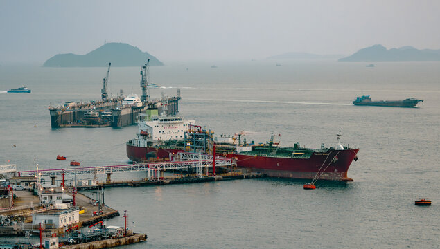 Hong Kong, China, 8 March 2026: oil tanker Silver Emily docked near Kwai Chung and Kwai Tsing container terminals with offshore fuel infrastructure and maritime traffic at sunset. 