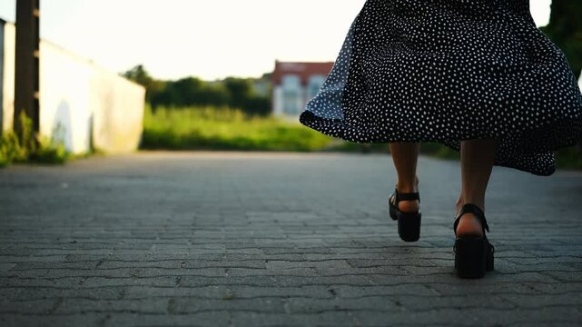 Young Woman In High-Heeled Shoes Walks Attractively Through The Historical Part Of A European City On A Summer Day