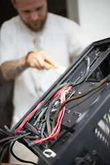 Fototapeta premium Person repairs computer case with wires and tools while focused on task in a well-lit room