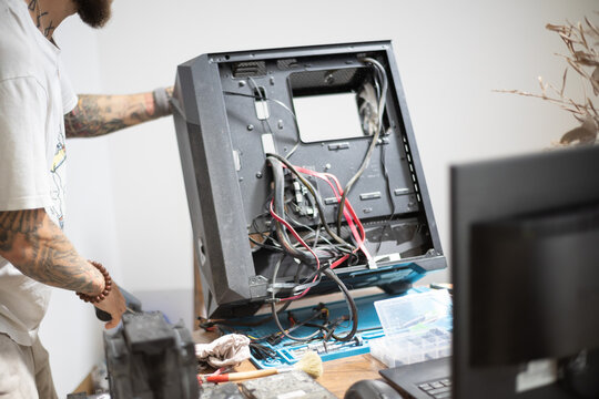 Man working on a computer case at a desk in a modern workspace during daytime