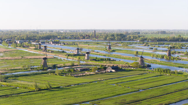 Aerial view of the historic Kinderdijk windmills standing along canals in the lush green polder landscape under a clear sky Kinderdijk, South Holland, Netherlands.