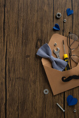 Naklejka premium Happy Father's Day gift vertical envelope with tools, bow tie, glasses and paper hearts on wooden table
