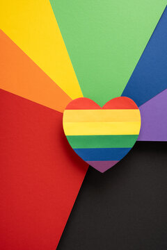 Paper vertical heart with rainbow stripes on colorful paper background for Pride Month celebration