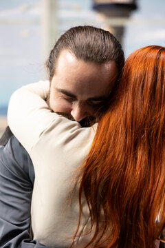 Emotional airport reunion with couple embracing upon arrival, hugging and smiling in intimate moment. Authentic sentimental scene capturing love, affection and joyful homecoming.