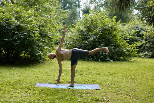 Man balances on hand and foot during peaceful park session