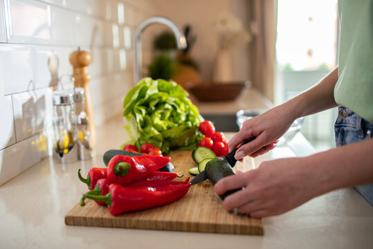 Person slicing cucumber on cutting board in home kitchen