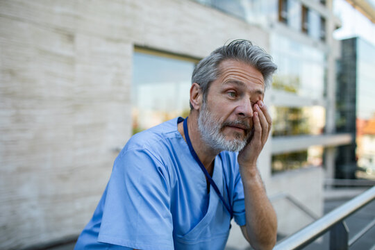 Tired male nurse rubbing eye outside hospital