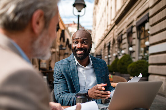 Smiling businessman meeting client at outdoor cafe