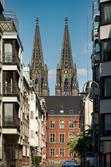 Obraz premium Impressive view of the Cologne Cathedral spires framed by urban buildings and the historic district court. A perfect blend of old and new architecture
