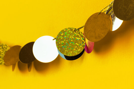Close-up of glitter and mirror disc garland on yellow background.