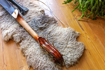 Broken contrabass neck joint with fingerboard, scroll and  tailpiece lying on the wooden floor with felted wool locks rug.   © Dina