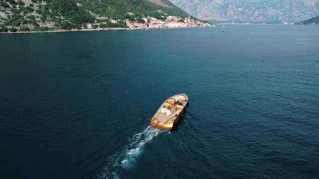 Vessel approaches tranquil village beneath peaks. Quiet boat arriving at rustic harbor surrounded by mountains
