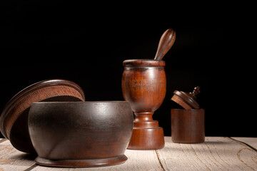 Wooden vessels, various wooden vessels on very old rustic wood, garlic press, black background, low-key style, selective focus. © Milton Buzon