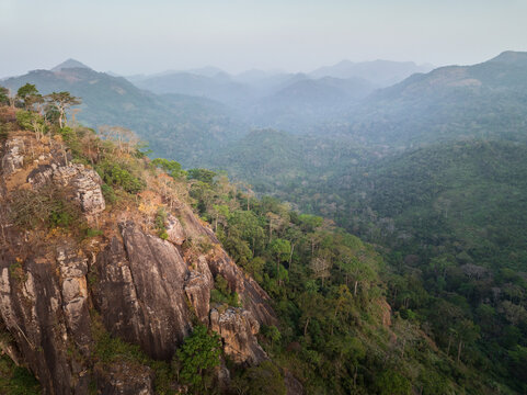 Aerial view of steep rocky cliffs and lush tropical forest stretching across the misty mountain valley near Man, Montagnes District, Cote d'Ivoire.