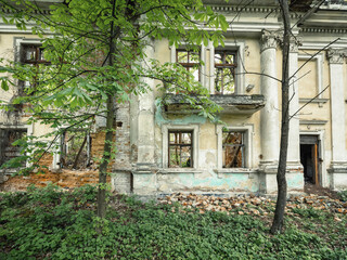 Fototapeta premium view to facade with balcony of old abandoned palace with spring trees