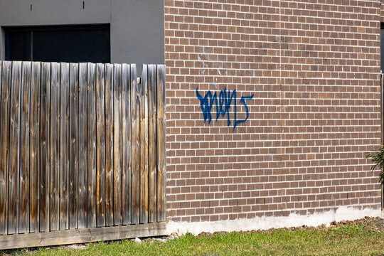 Blue graffiti tag vandalism on a wall of a residential house in a Melbourne suburb.Urban decay and vandalism in residential neighborhood. Urban decay and antisocial behaviour issue in Australia