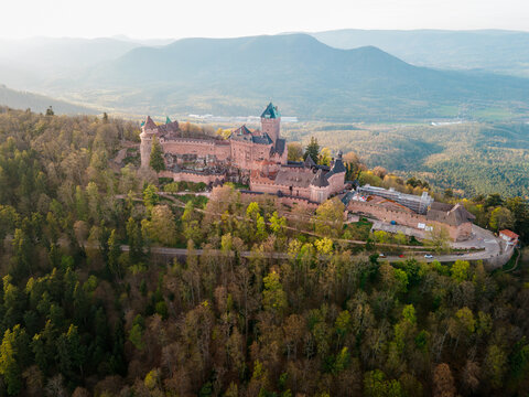 Castle Haut-Koenigsbourg, Alsace, France - April 10, 2026 - Aerial fortress silhouette on wooded plateau during late afternoon, long shadows emphasizing ramparts and central keep, engineered layout
