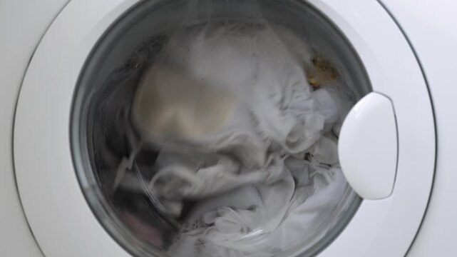 Interior view of washing machine drum with textiles spinning during laundry process. Concept appliance operation and hygiene.
